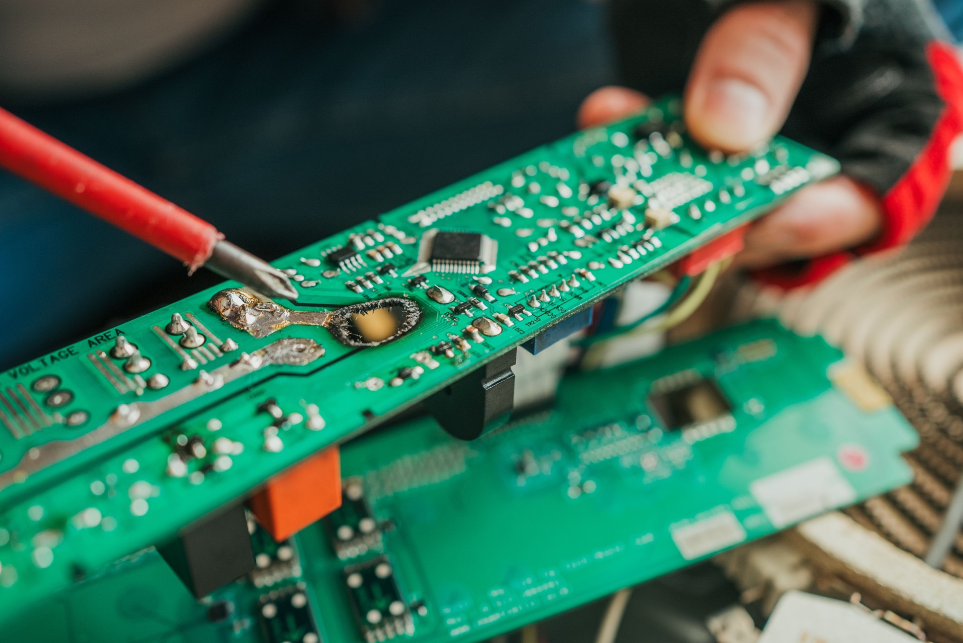 Tecnico qualificato che ripara schede elettroniche danneggiate, saldando accuratamente componenti complessi con precisione professionale e competenza tecnica mirata