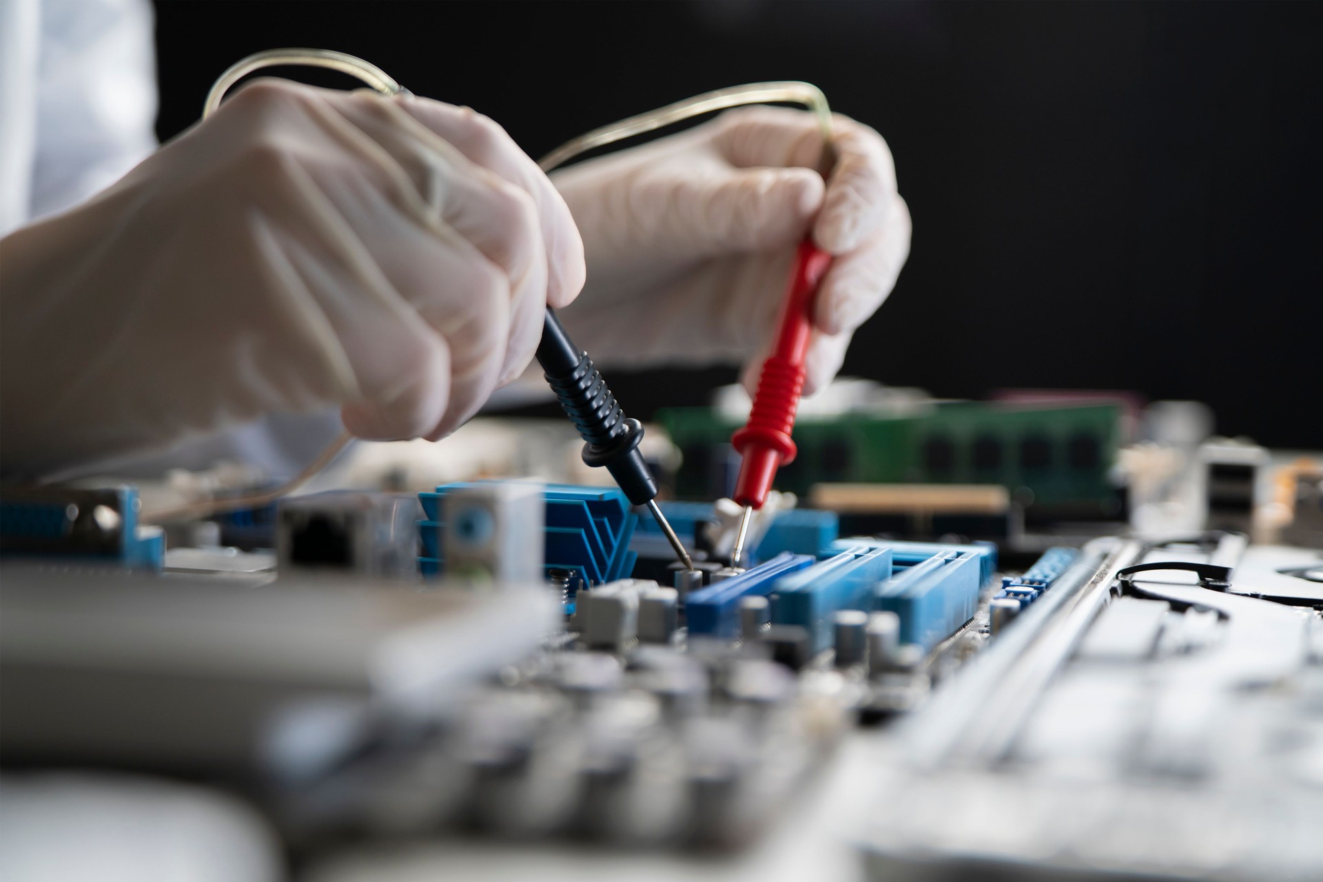 una persona che tiene in mano uno strumento multimetro e che effettua misurazioni sulla scheda del computer PCB